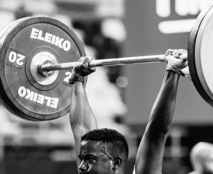 Black and white photo of an athlete holding a loaded barbell overhead