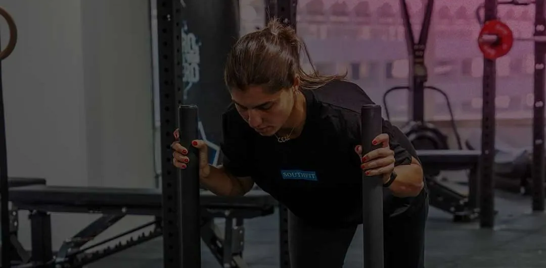 Woman in a SouthFit T-shirt pushing a sled loaded with green plates