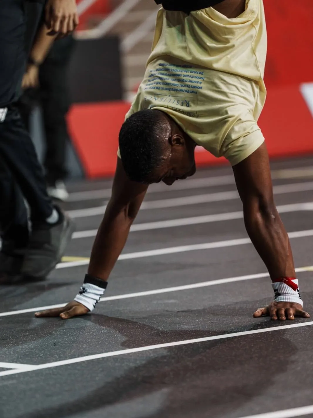 Close-up of an athlete mid handstand walk, hands flat on the track and wrists taped